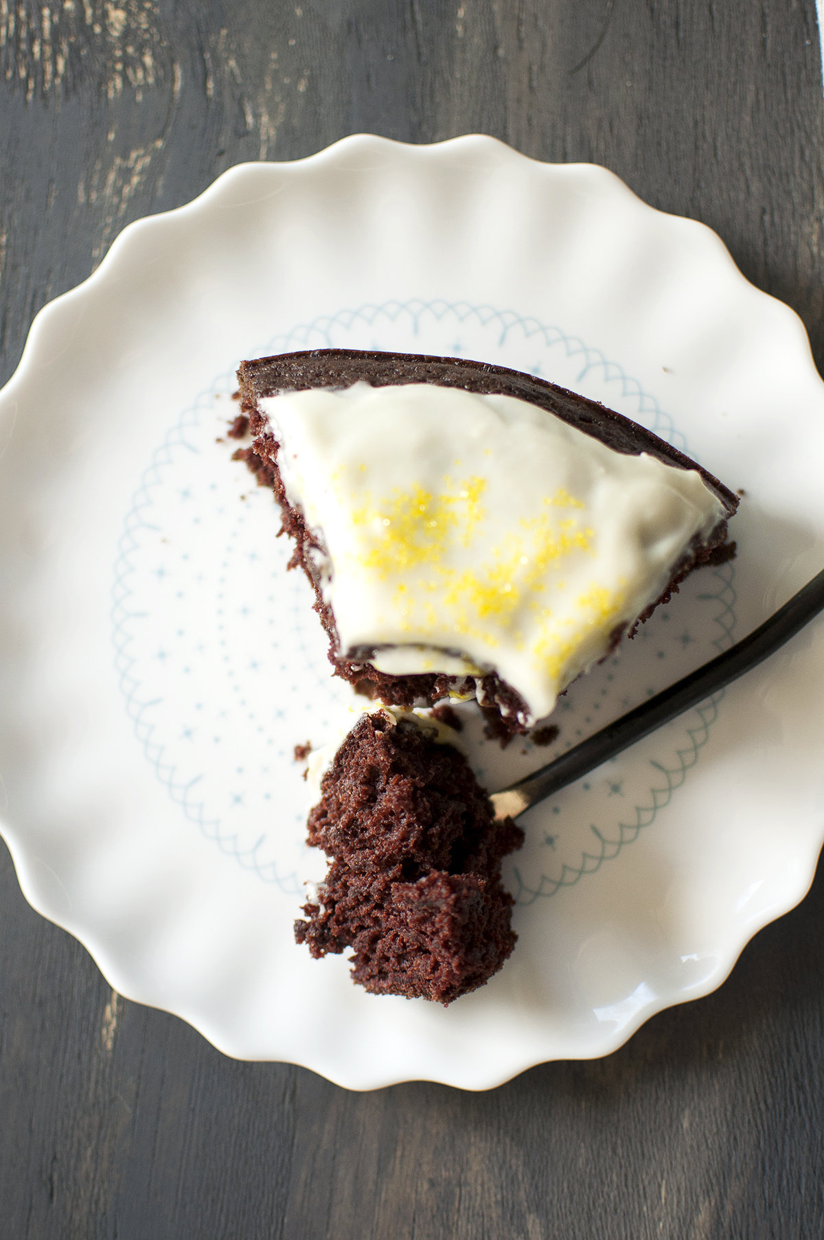 White plate with a slice of cake that is cut into with a fork