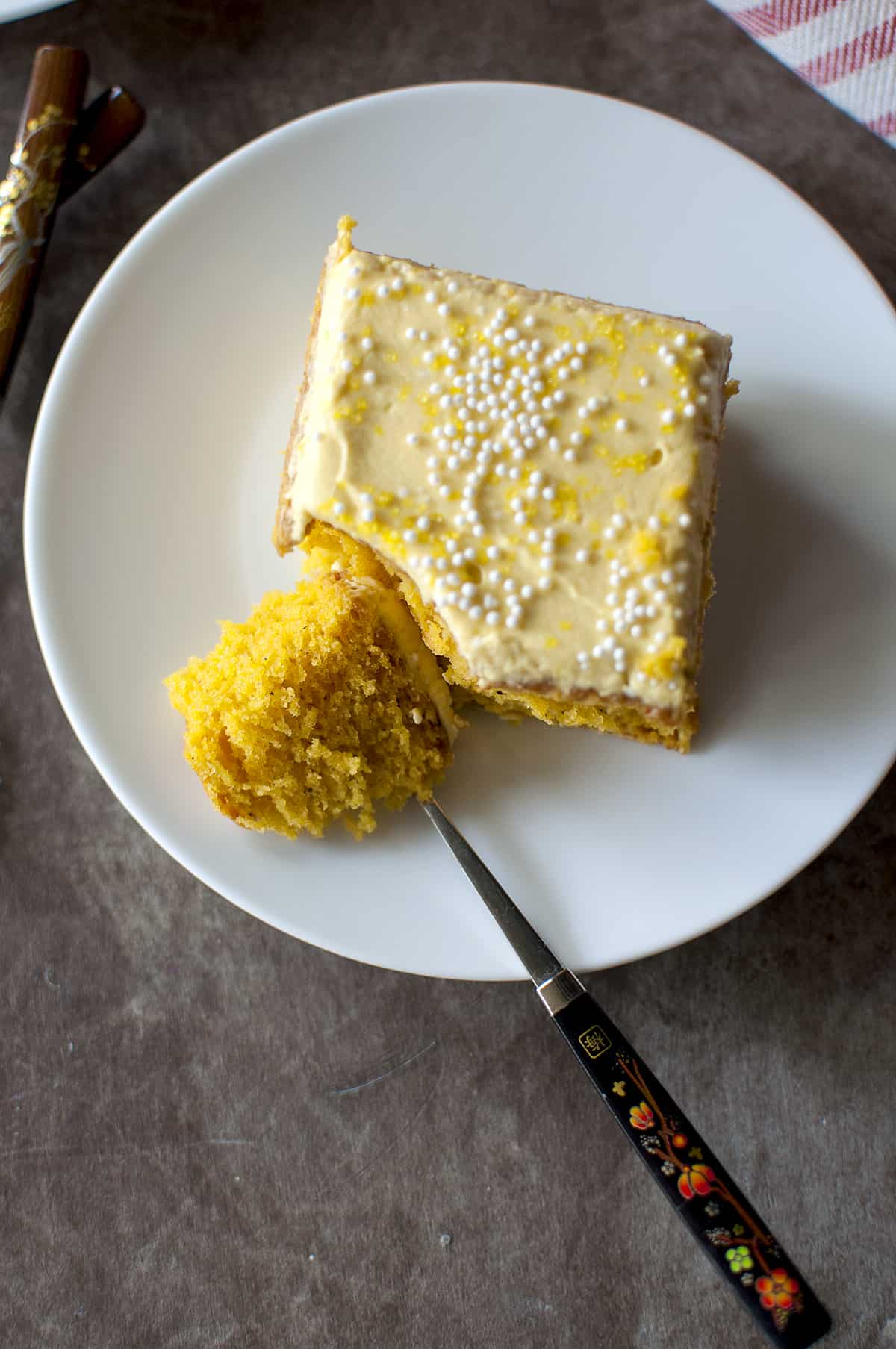 White plate with a square slice of cake that is cut with a spoon.