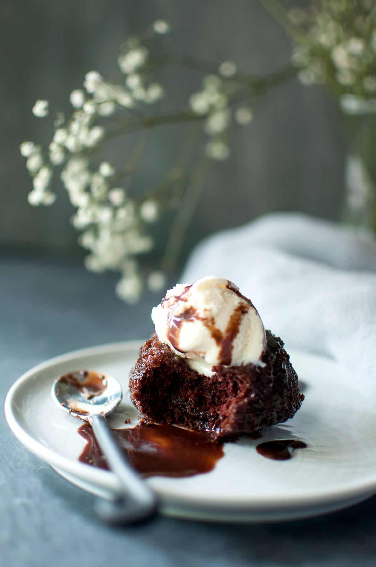 White plate with half cupcake topped with ice cream.