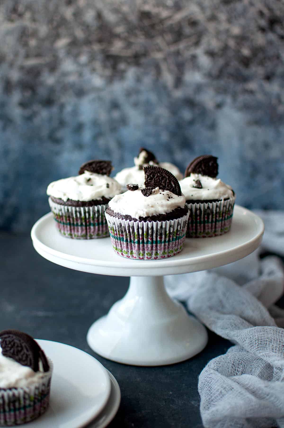 White cake stand with chocolate oreo cupcakes.