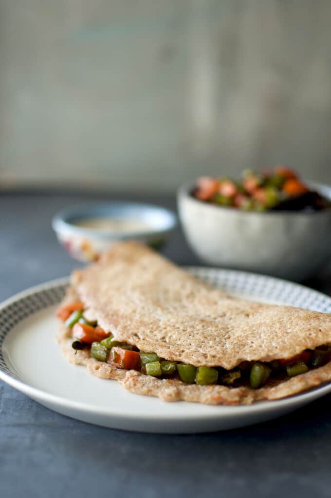 White plate with instant wheat dosa stuffed with carrot & green bean saute