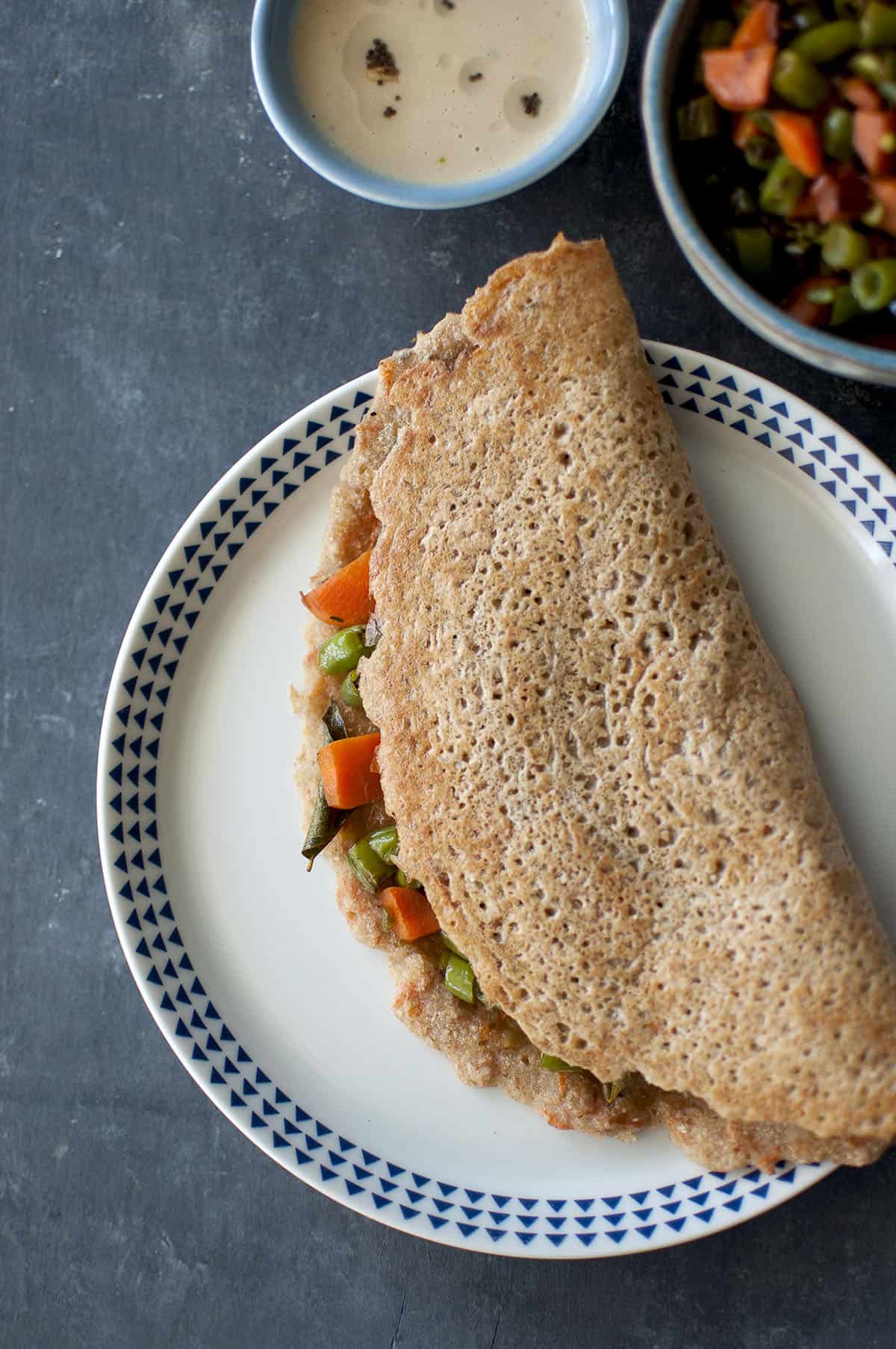 White plate with instant wheat dosa stuffed with carrot & green bean saute