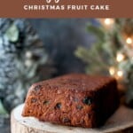 Loaf of vegan fruit cake on a wooden cake stand.