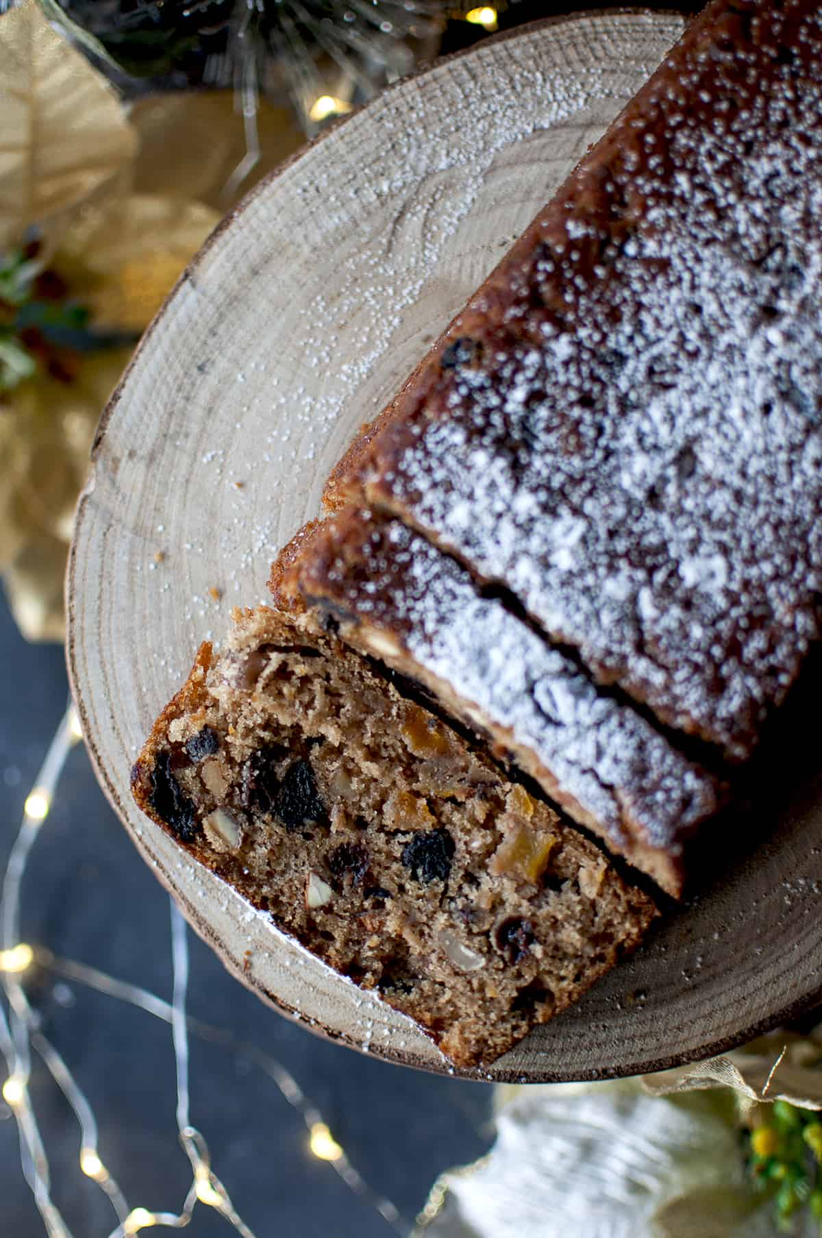 Sliced eggless plum cake on a wooden stand