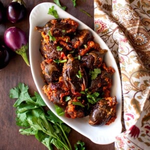 White oval bowl with stuffed brinjal fry.