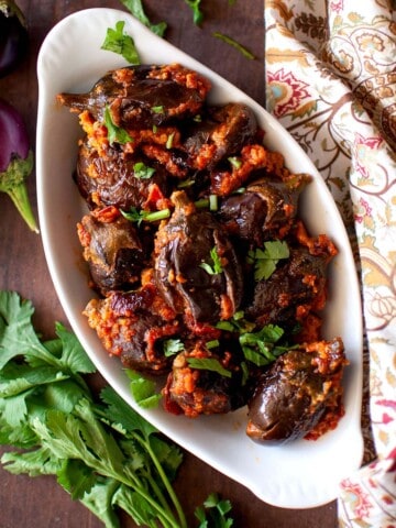 White oval bowl with stuffed brinjal fry.