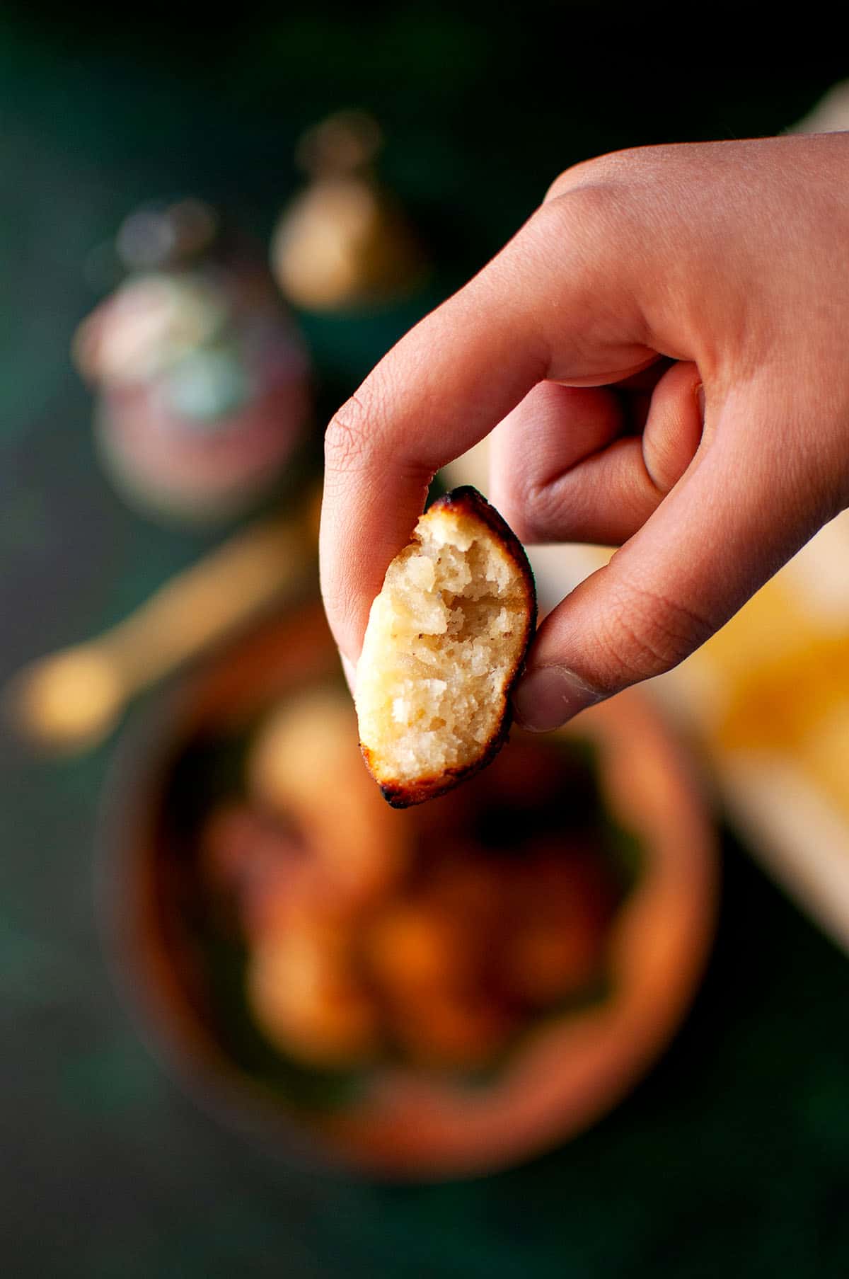 Hand holding half a unni appam.