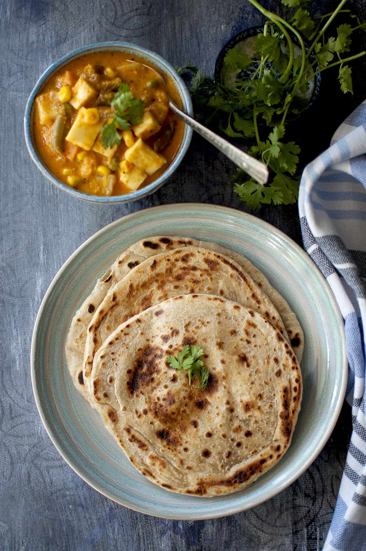 Blue plate with 3 Kerala Parotta and a bowl of vegetable curry