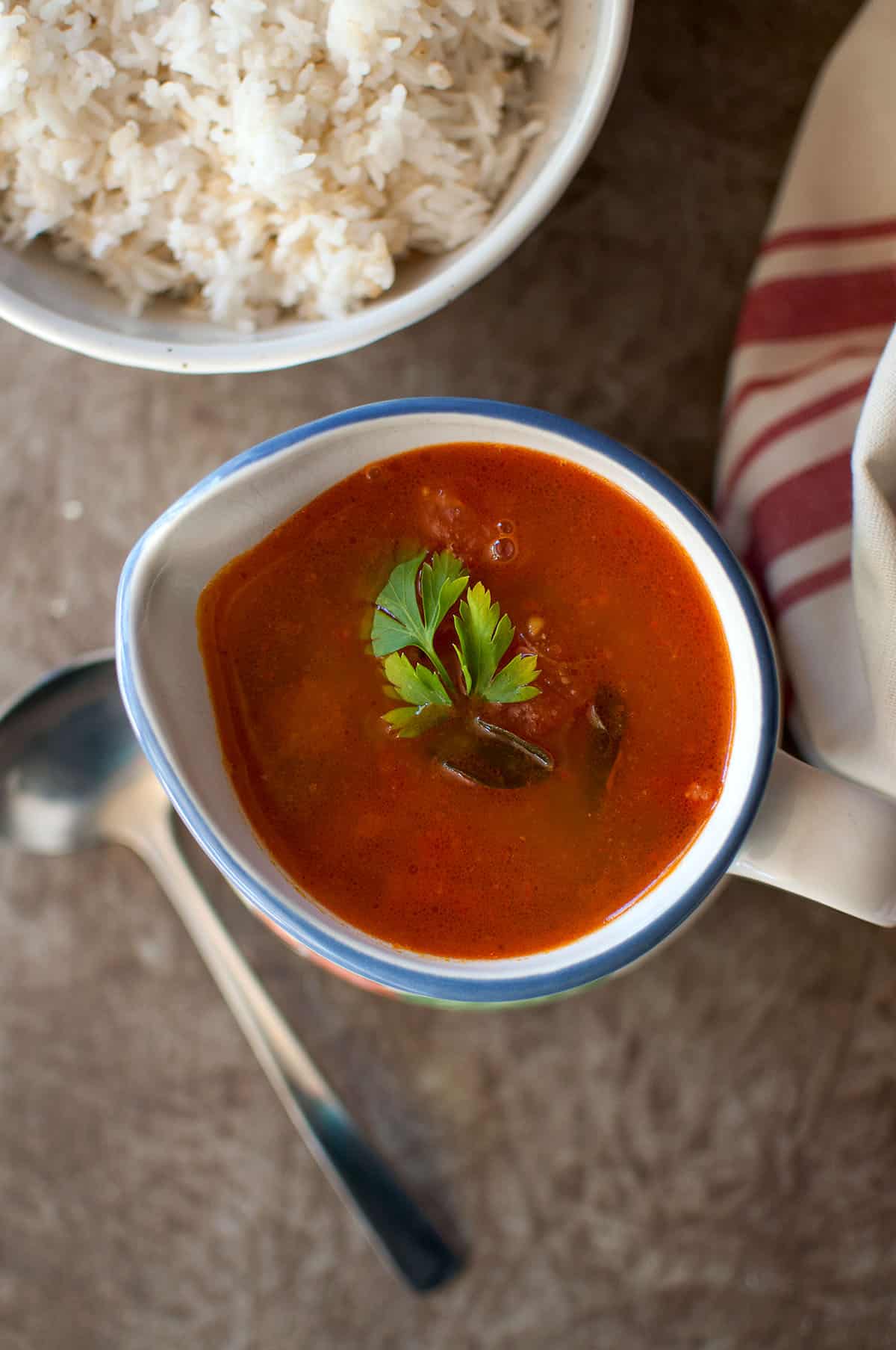 White bowl with tomato mixed dal rasam and rice.