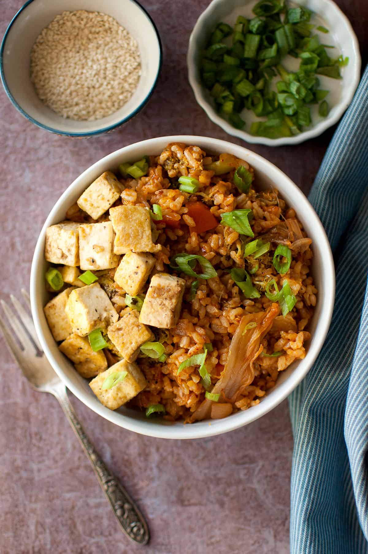 Top view of white bowl with vegetarian kimchi fried rice topped with crispy tofu.