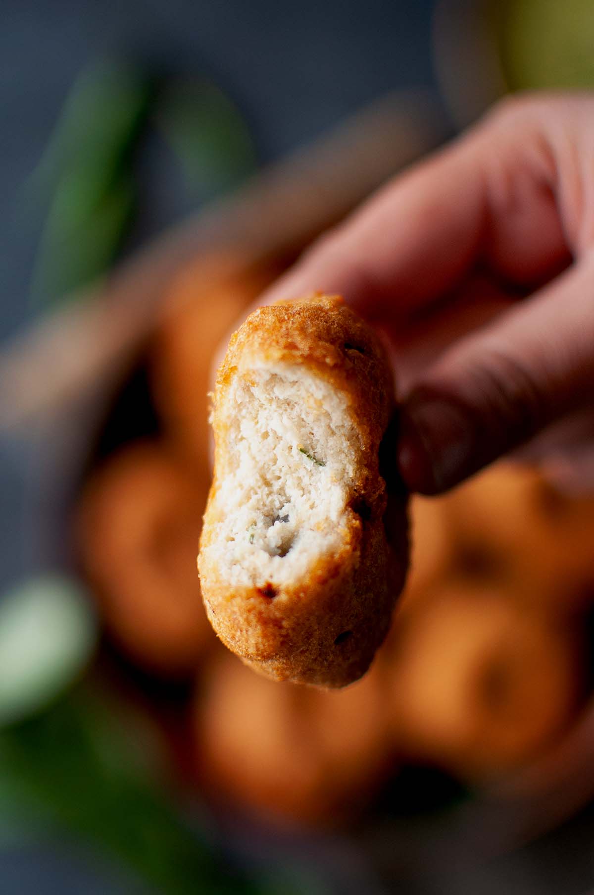 Hand holding half a medu vadai.