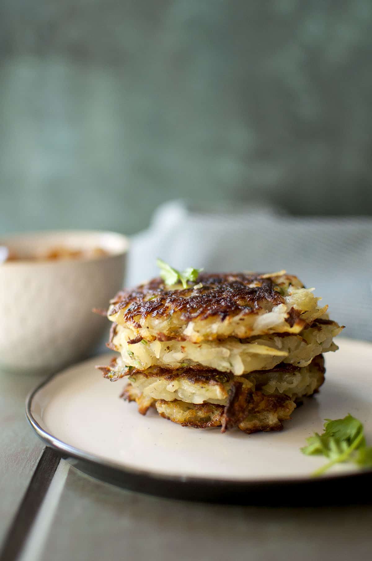 White plate with crispy potato latkes topped with parsley