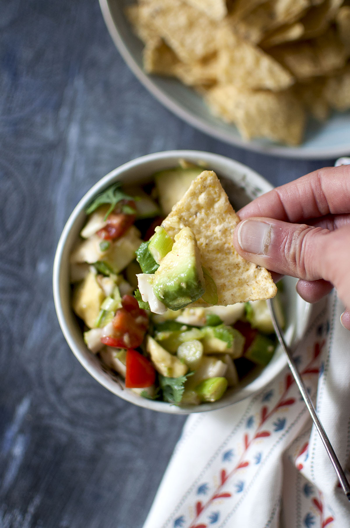 Hand holding a tortilla chip topped with coconut ceviche