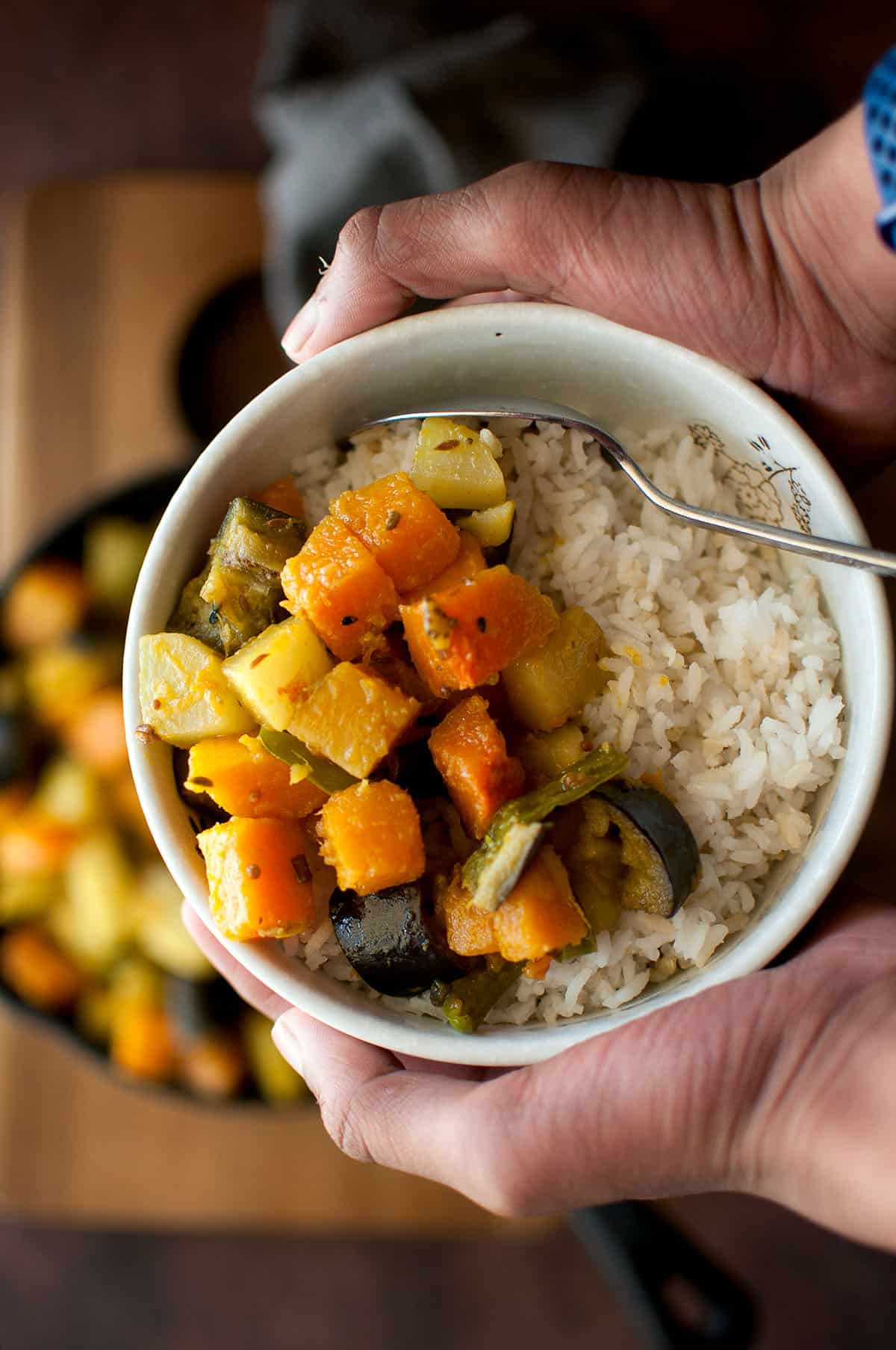 Hands holding a bowl of rice and labra.