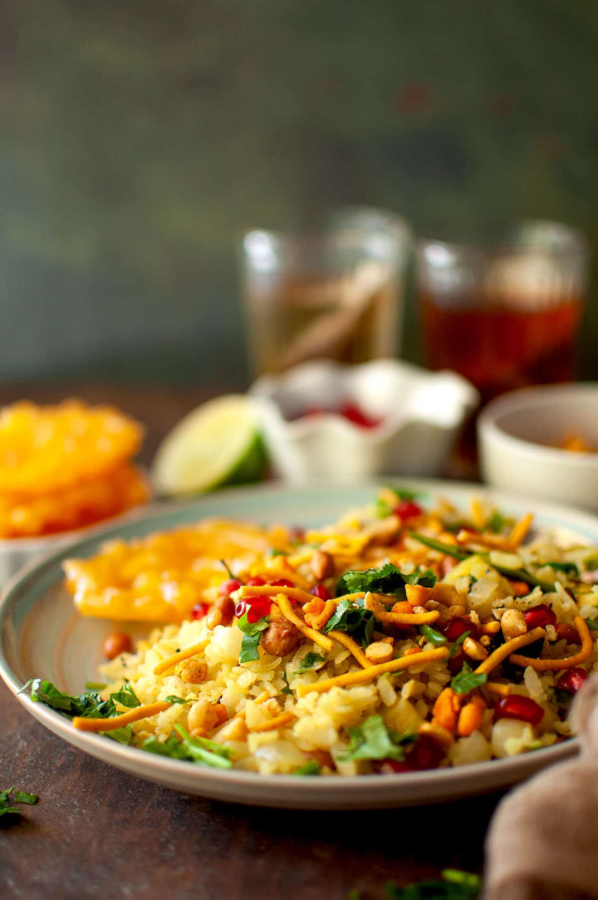 Plate with indori poha topped with sev and pomegranate seeds.