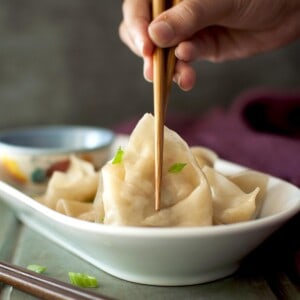 Hand holding vegetarian momos with chopsticks