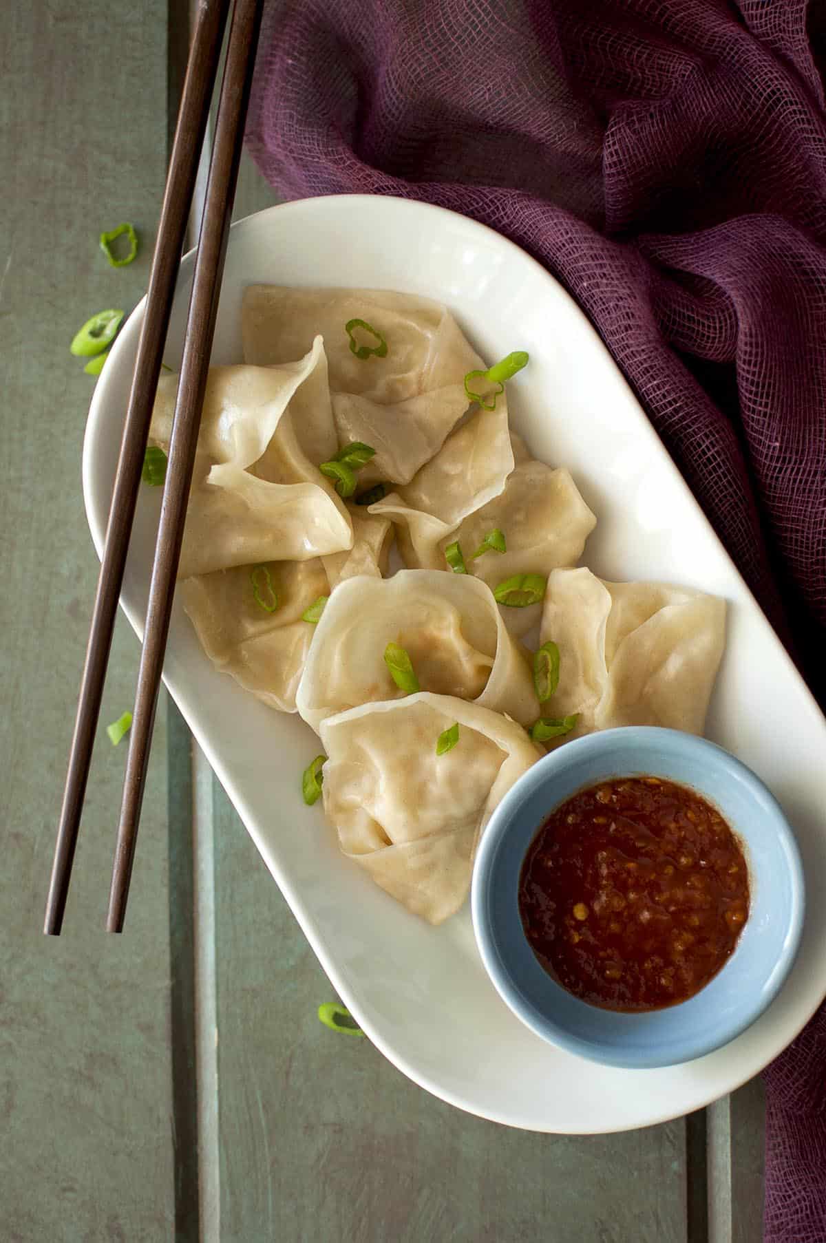 White bowl with steamed Vegetarian Momos and a bowl of chili sauce