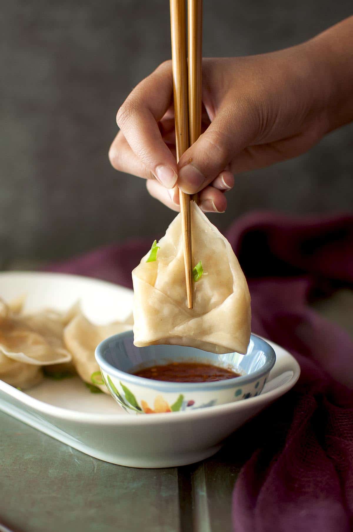 Hand holding vegetarian momos with chopsticks