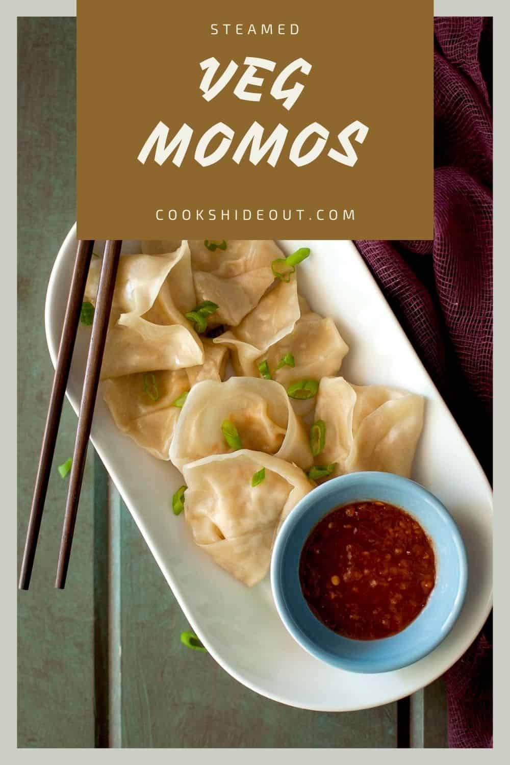 White plate with steamed veg momos and a blue bowl with chili sauce