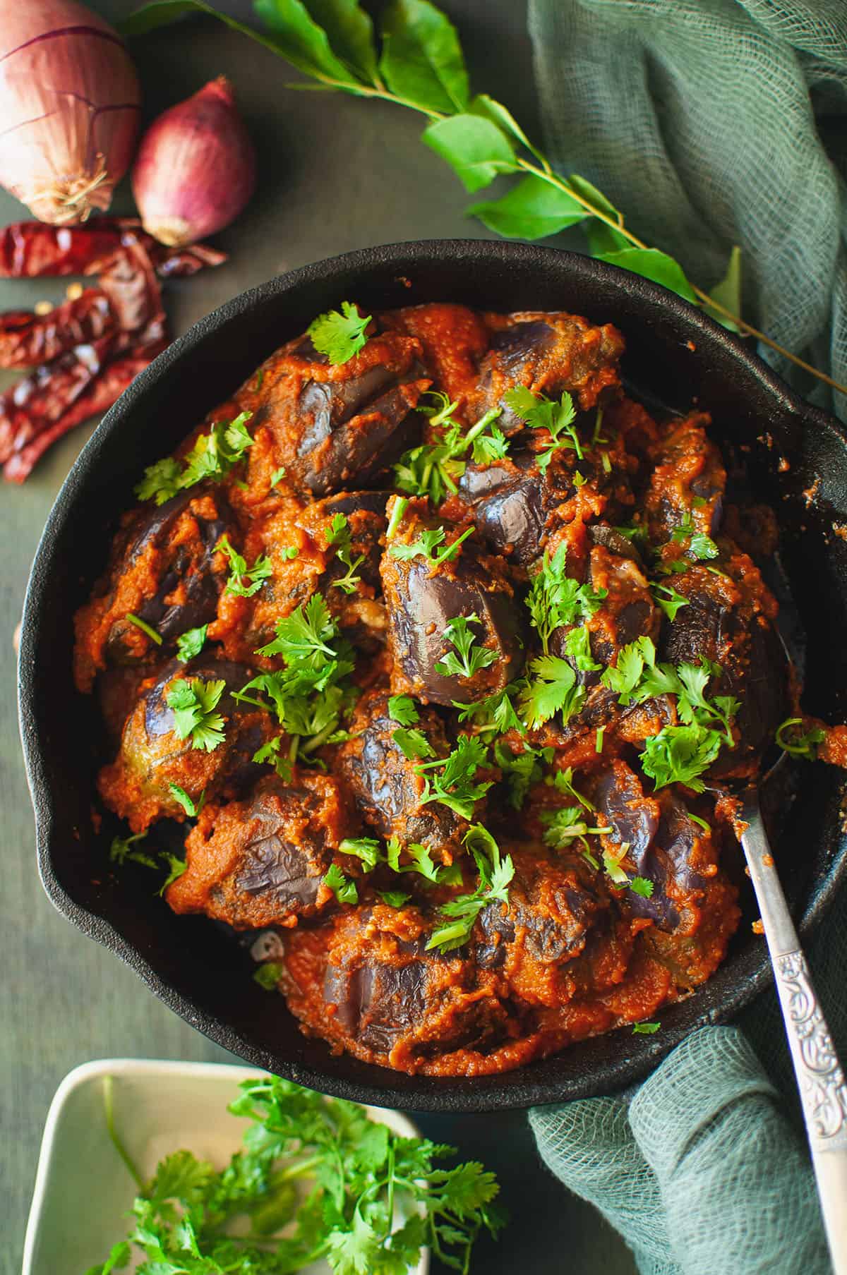 Cast iron pan with spicy egglant curry topped with cilantro.