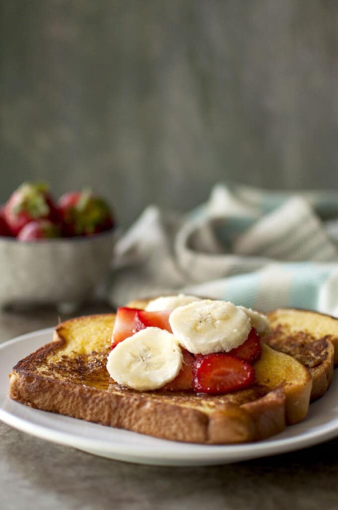 white plate with French toast topped with chopped fruit