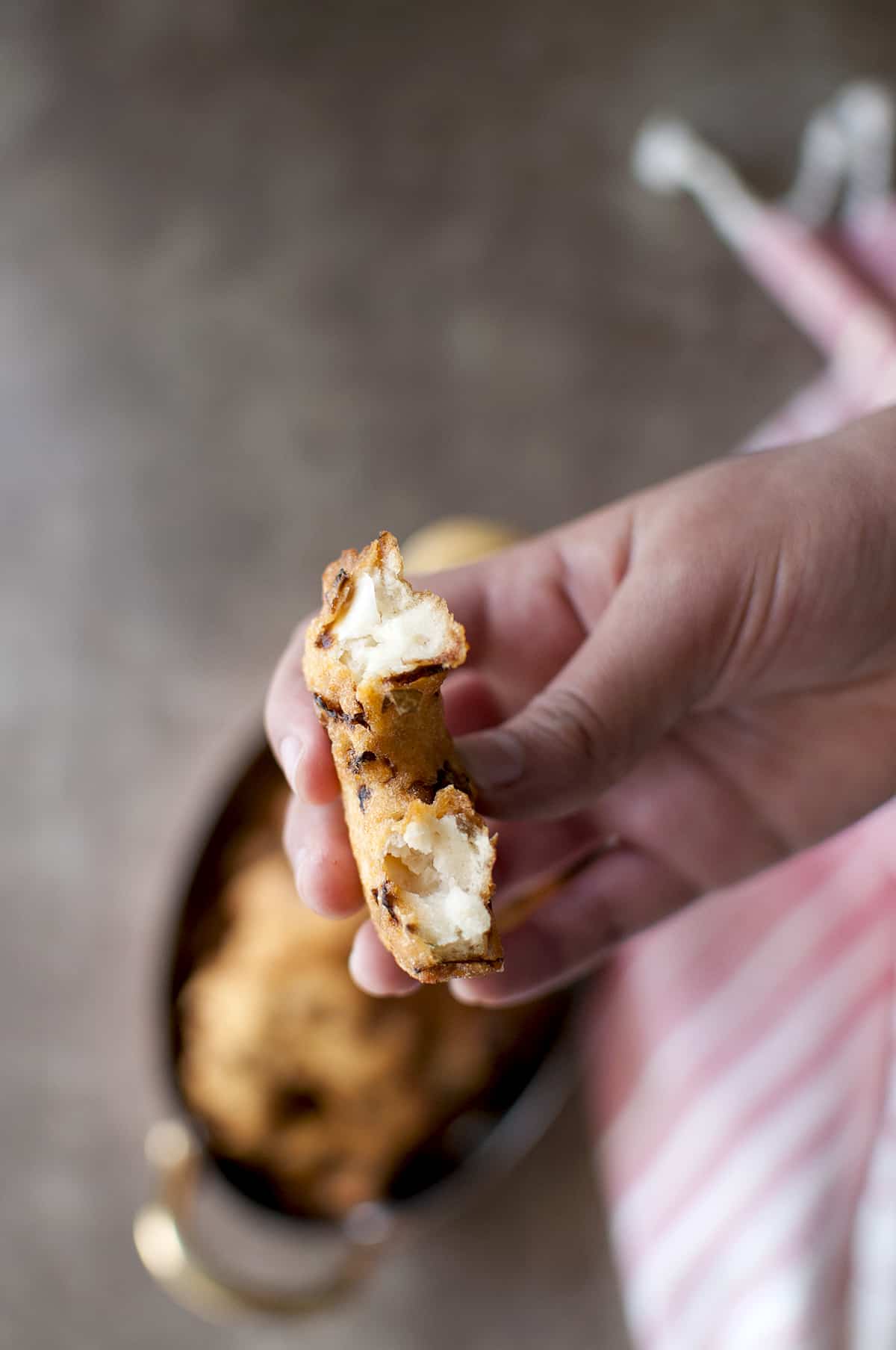 Hand holding half cabbage vada showing the fluffy interior