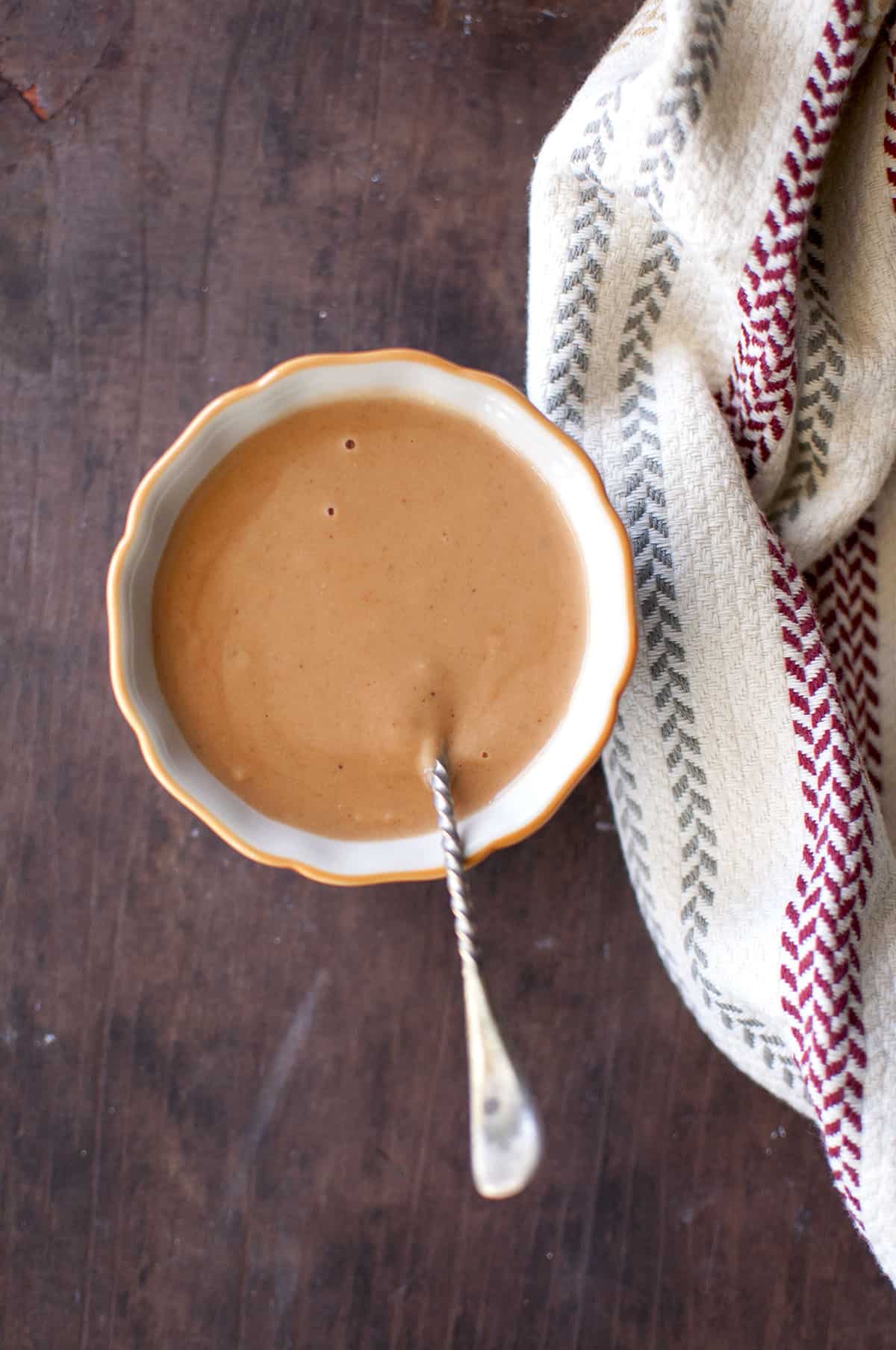 White bowl with groundnut sauce with a spoon inside