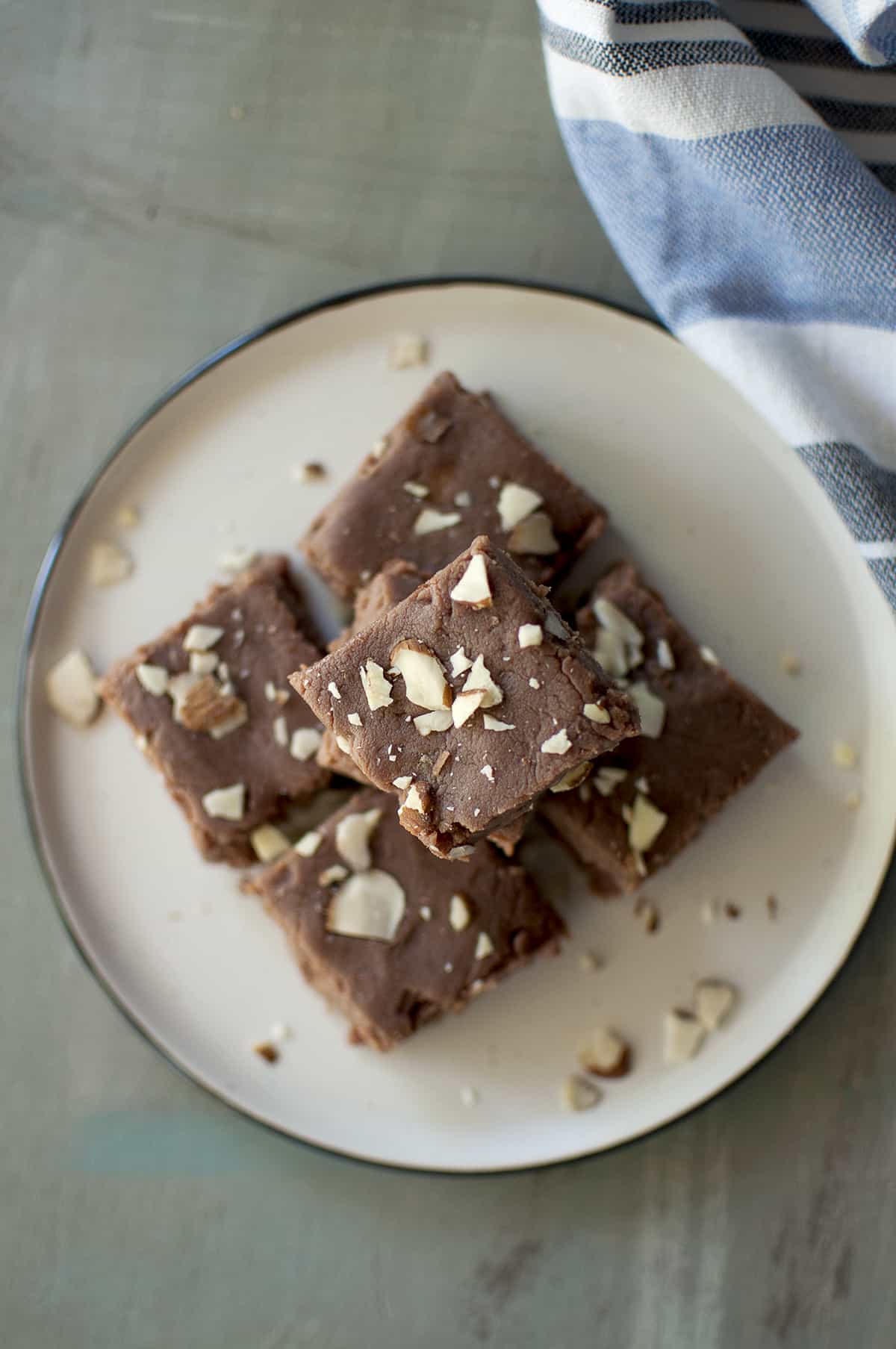 Grey plate with a stack of chocolate burfi squares topped with sliced almonds