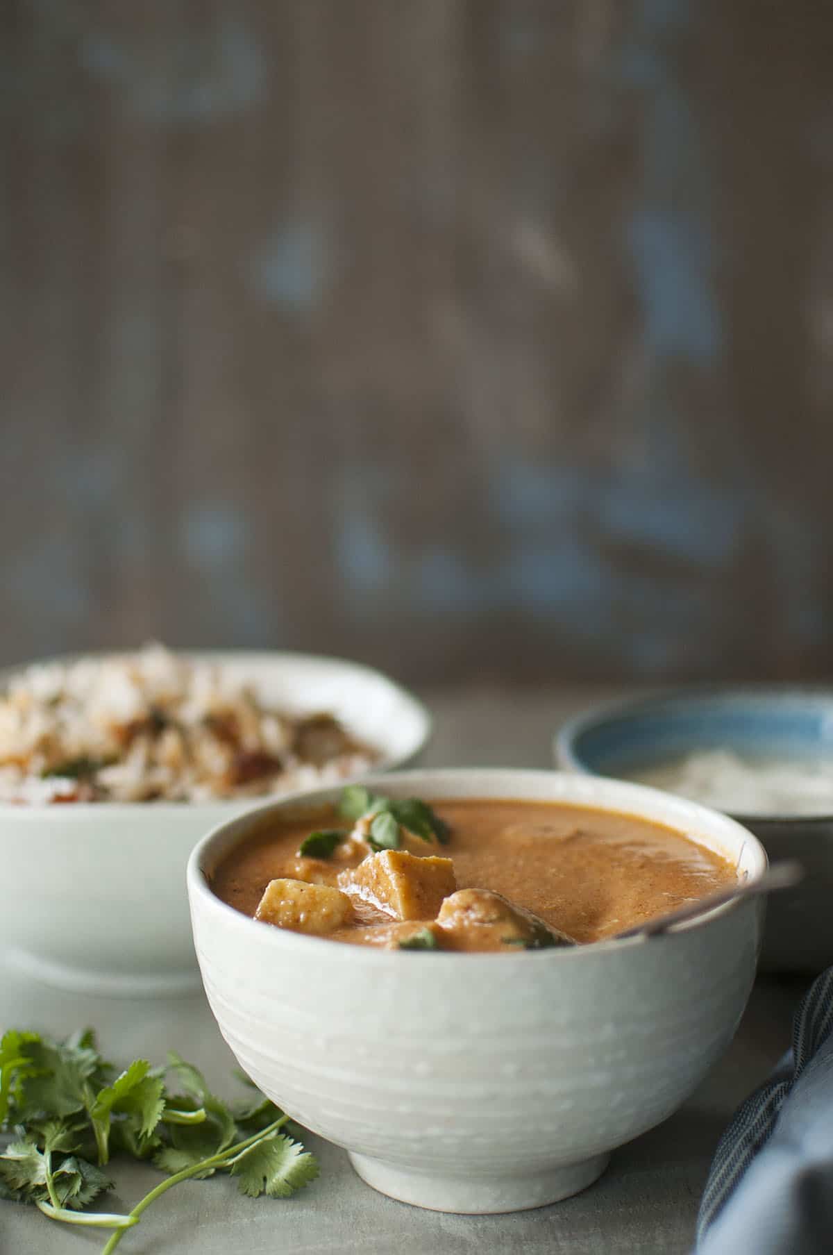 White bowl with paneer curry topped with cilantro