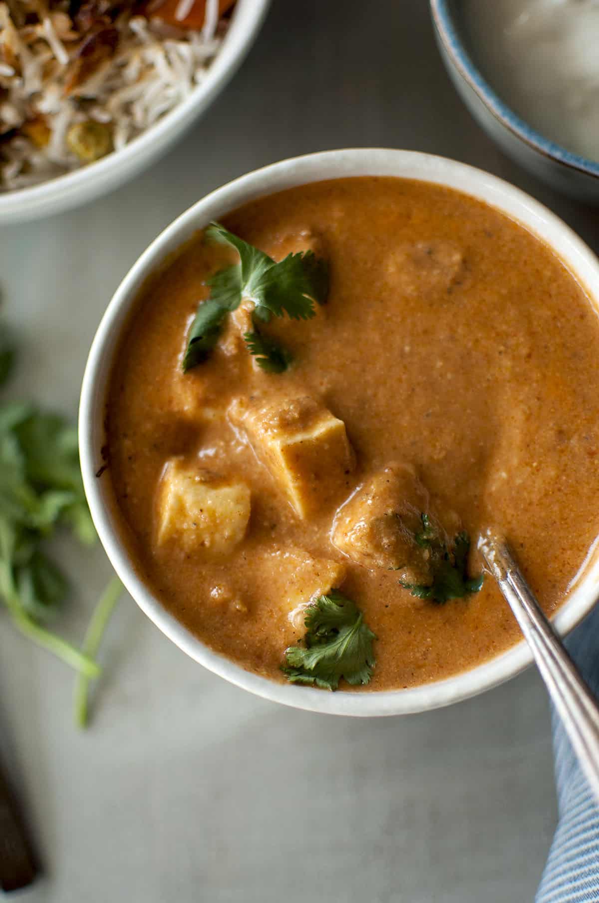 White bowl with Kashmiri Paneer tikka masala topped with cilantro