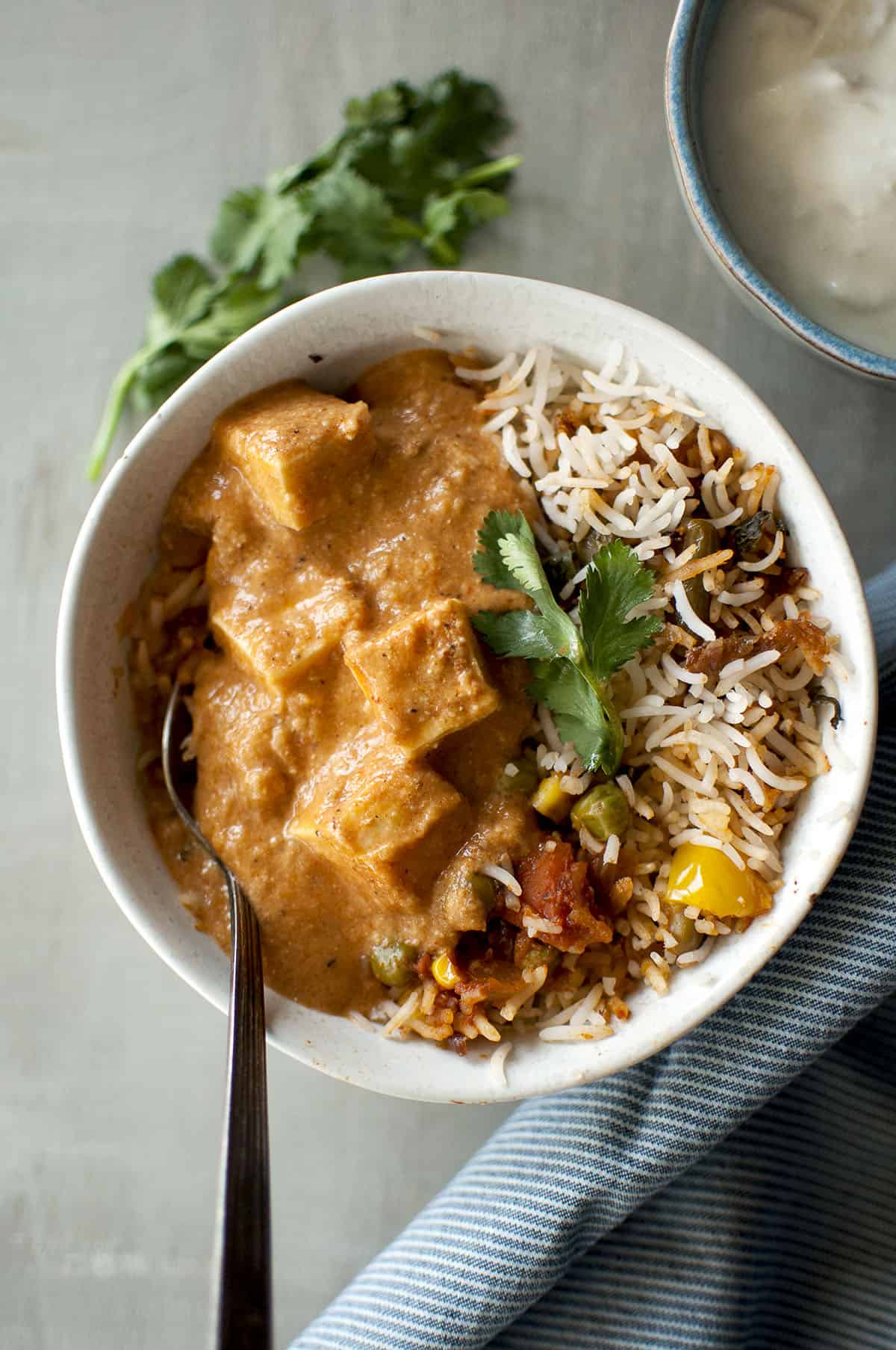 White bowl with rice pilaf and paneer curry