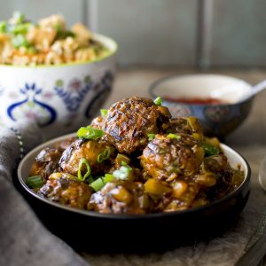 Black plate with a stack of veg manchurian.