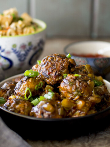 Black plate with a stack of veg manchurian.