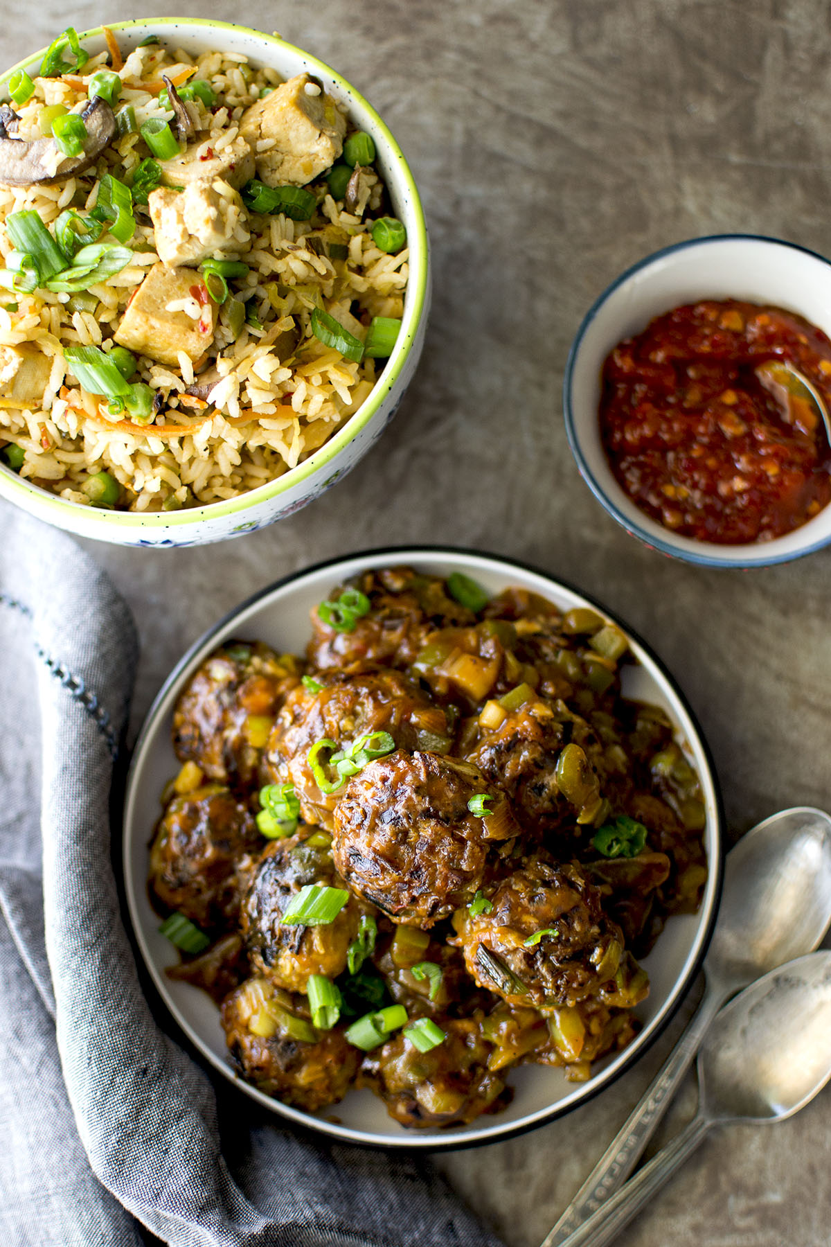 Bowl with Indo-Chinese saucy vegetable fritters with fried rice and chili sauce in the background