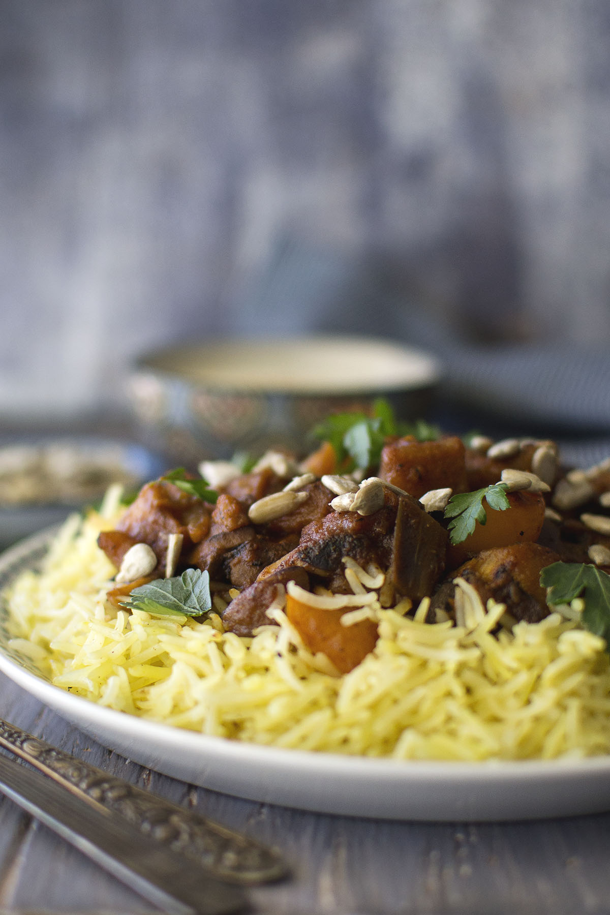 White plate with yellow rice, vegetables, sunflower seeds and parsley