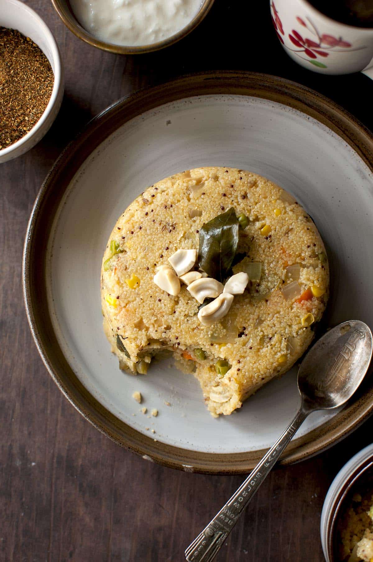 Grey plate with savory millet porridge and a spoon