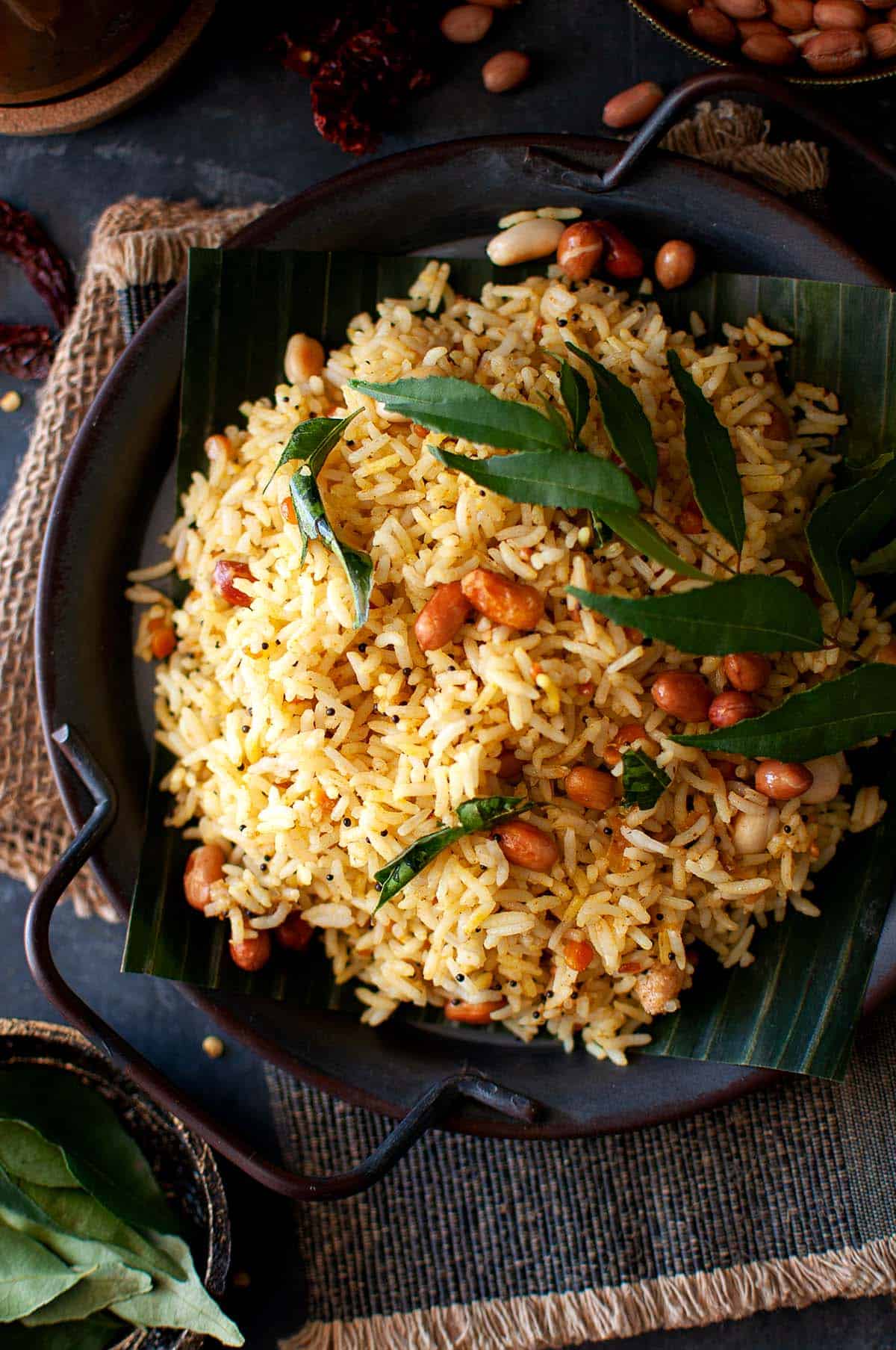 Top view of tamarind rice topped with peanuts and curry leaves.