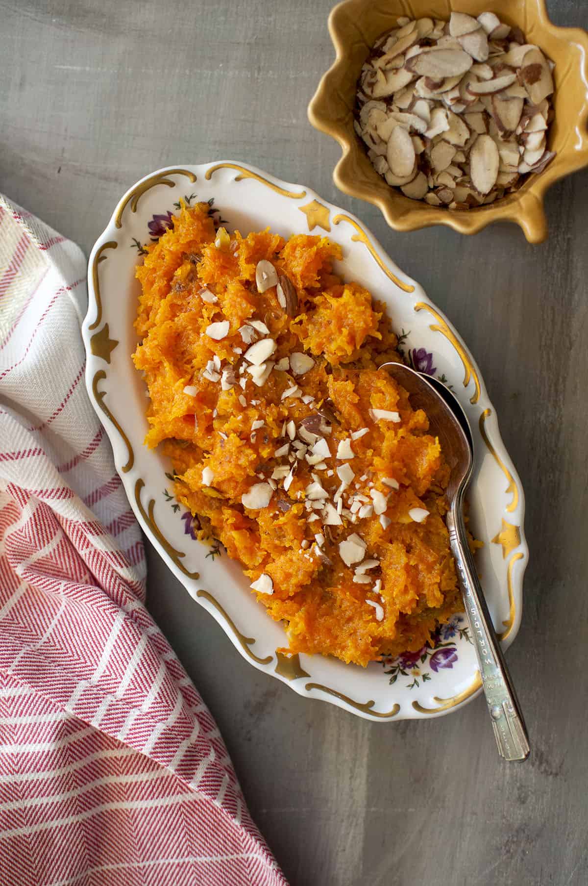 White oval bowl with Afghani carrot halwa topped with almond slices