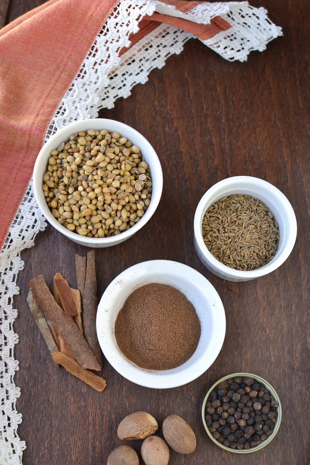 Ingredients needed for the recipe - White bowls with whole spices - coriander, cumin, allspice, peppercorn, cinnamon and nutmeg