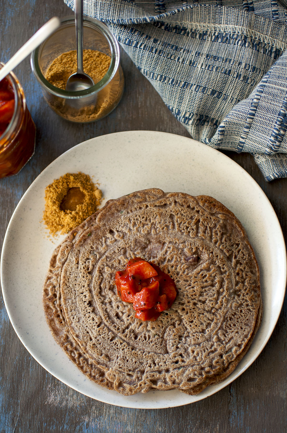 Grey plate with ragi adai topped with mango pickle and chutney powder