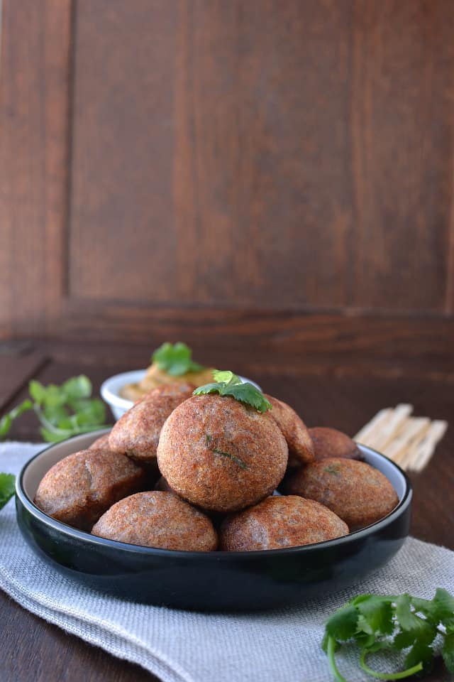 Black ceramic plate with south indian style aebleskivers and cilantro