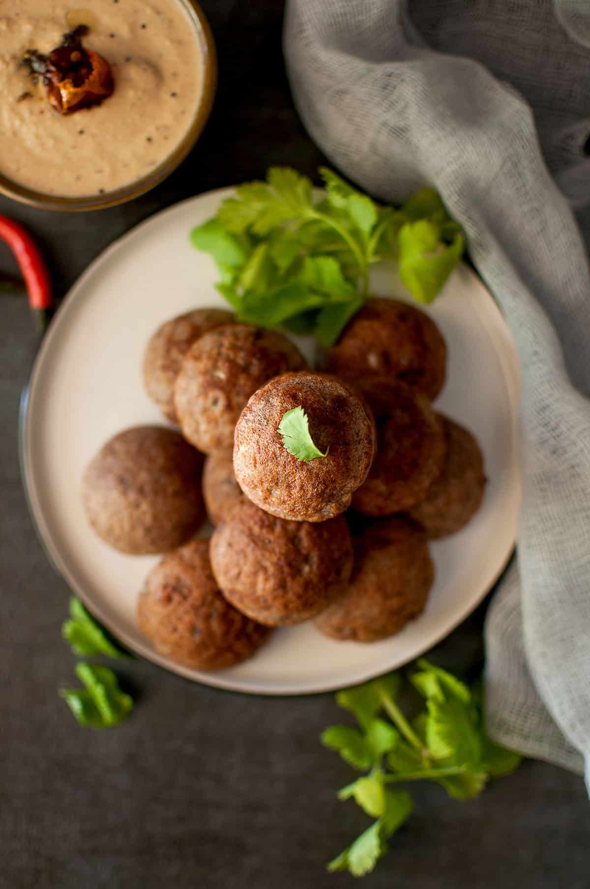 Grey plate with a stack of ragi paniyaram.