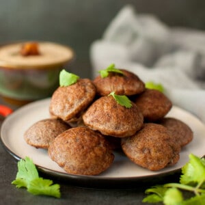 Grey plate with stack of ragi paniyaram topped with cilantro.