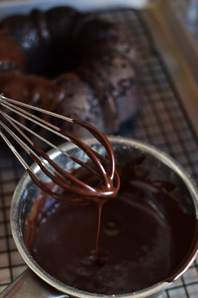 Whisk dripping chocolate frosting into a bowl.