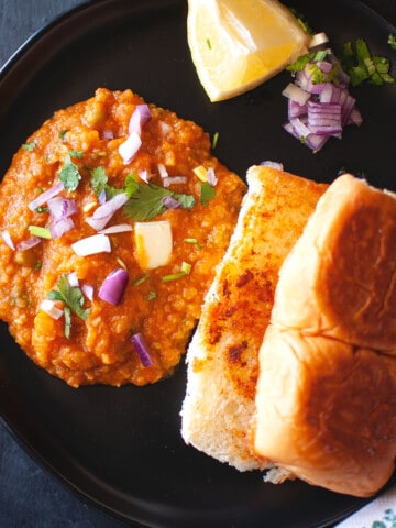 Black plate with pav bhaji.