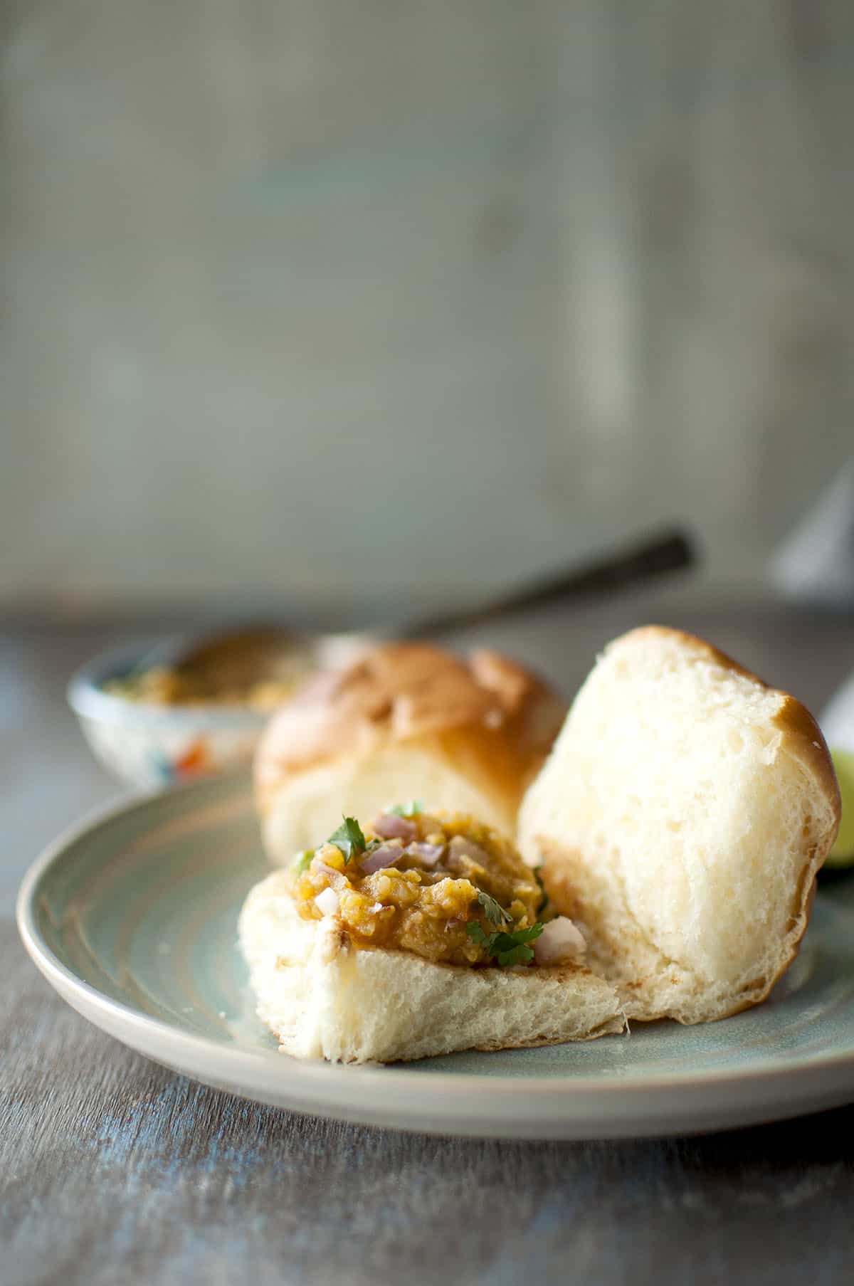 Blue plate with bun topped with bhaji.