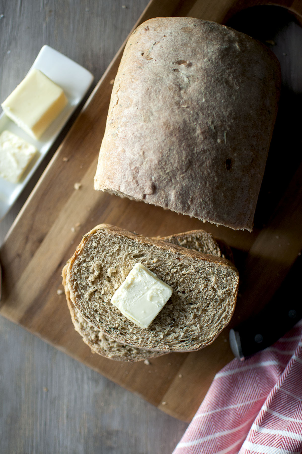 Chopping board with sliced bread topped with pat of butter