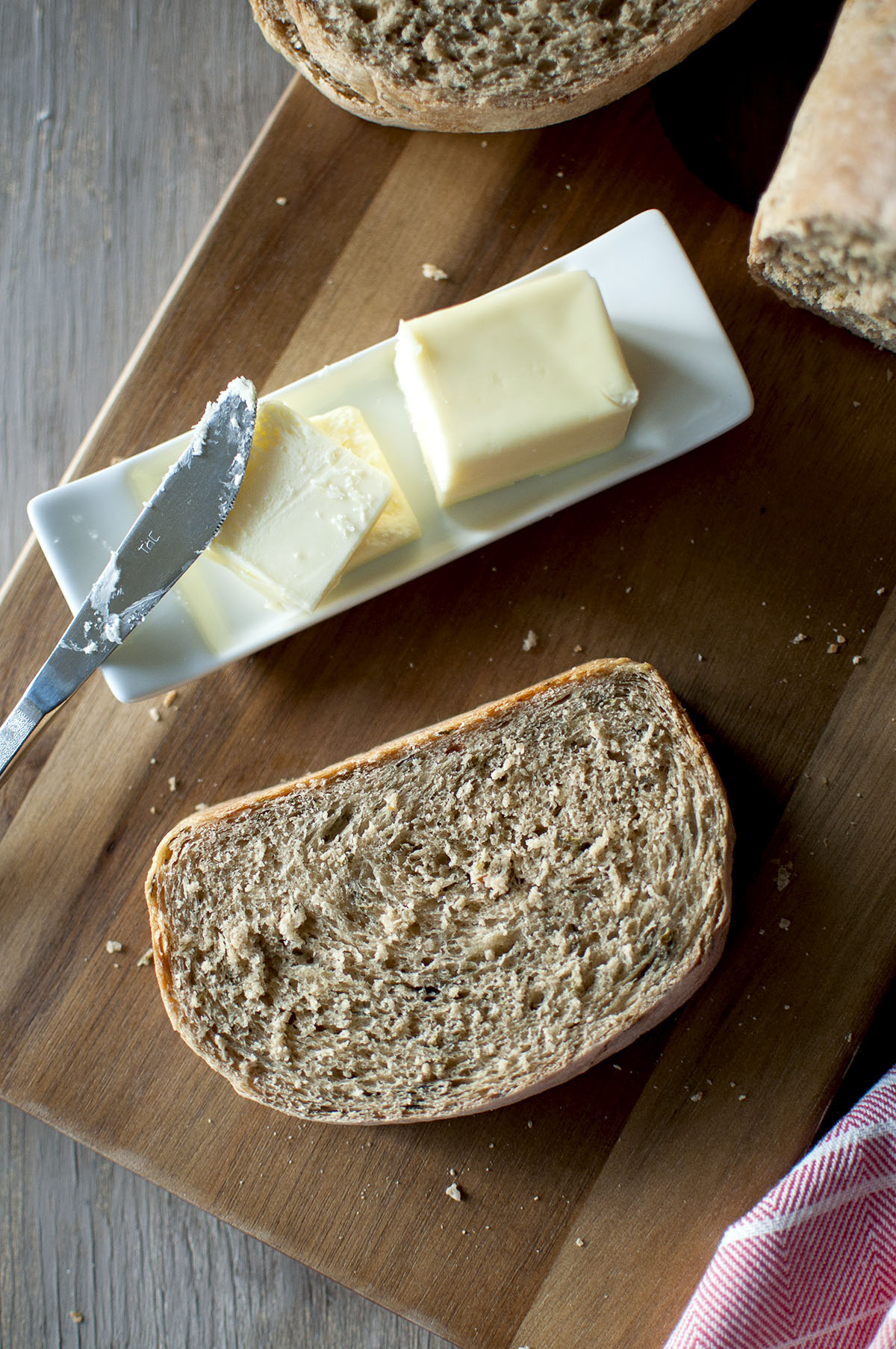 chopping board with sliced khara bread and a butter plate with butter and knife