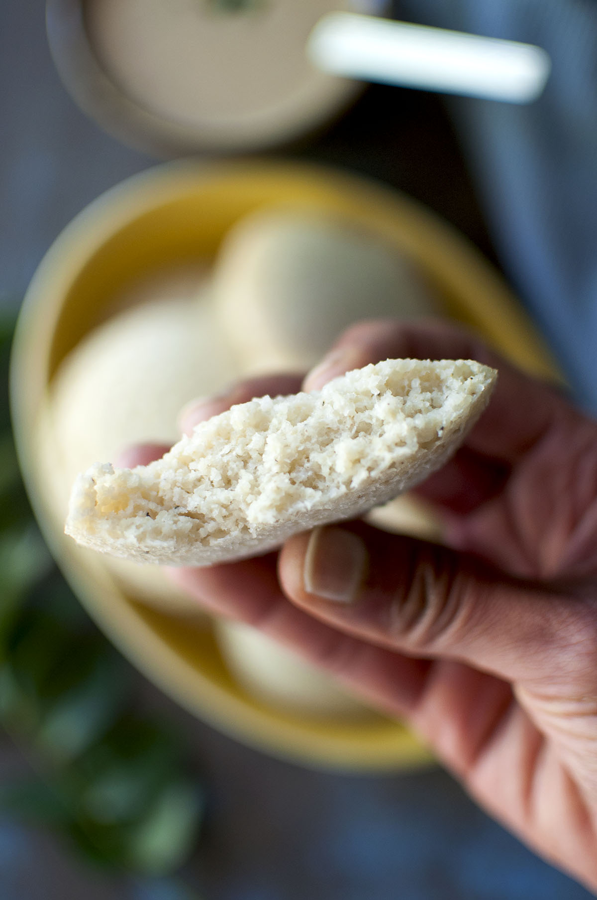 Hand holding half idli showing the inside texture