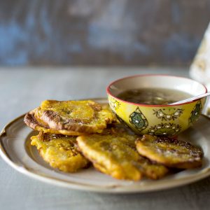 Plate with fried plantains and a bowl with garlic sauce.